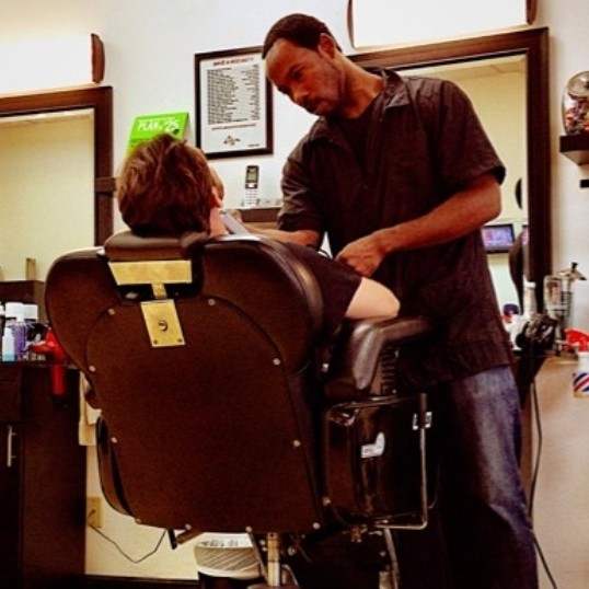 Barber cutting a young customer's hair in the shop